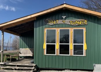 Green building with a porch swing and "Bait N Thangs" sign with bright yellow oars