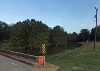 Bridge over creek with grassy area during the day