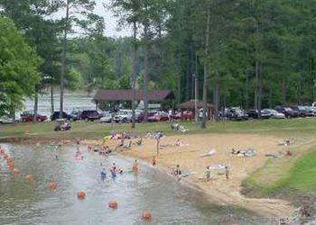 Swimming area with a sandy beach and pavilion. 