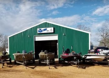 Bright green building behind a row of bass boats during the day