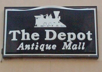 Black sign with white lettering that reads "The Depot Antique Mall"