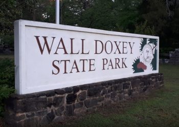 White sign that reads "Wall Doxey State Park" on top of stone. 