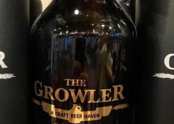 Amber colored growler with gold lettering that reads "The Growler - A Craft Beer Haven. Oxford, MS"