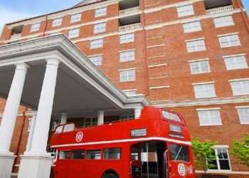 Exterior view of the Inn at Ole Miss with a bright red bus. 