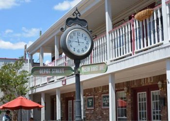 Storefronts in main street with balconies and old clocks with street signs