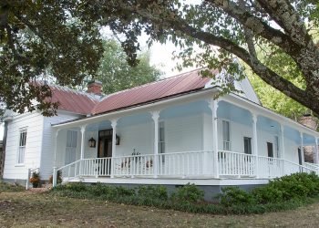 Exterior of Taylor Inn with a wrap-around porch and rocking chairs 