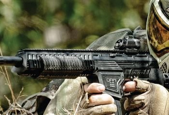 Man holding a paintball gun looking through a scope