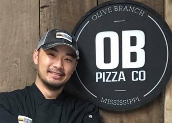 man smiling next to OB pizza sign