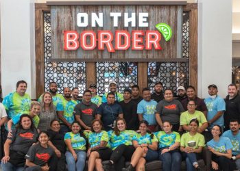 On the Border sign and staff smiling underneath